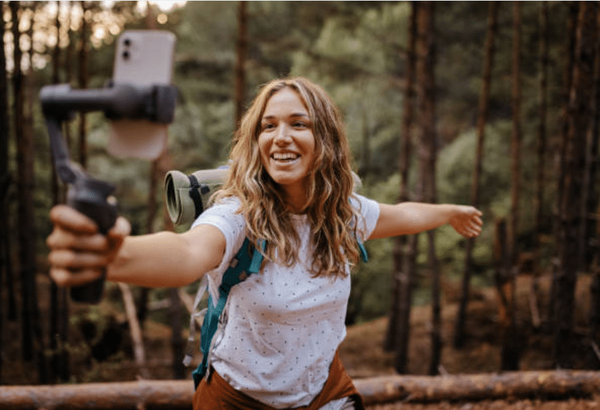Giovane donna gira un video nel bosco con lo smartphone